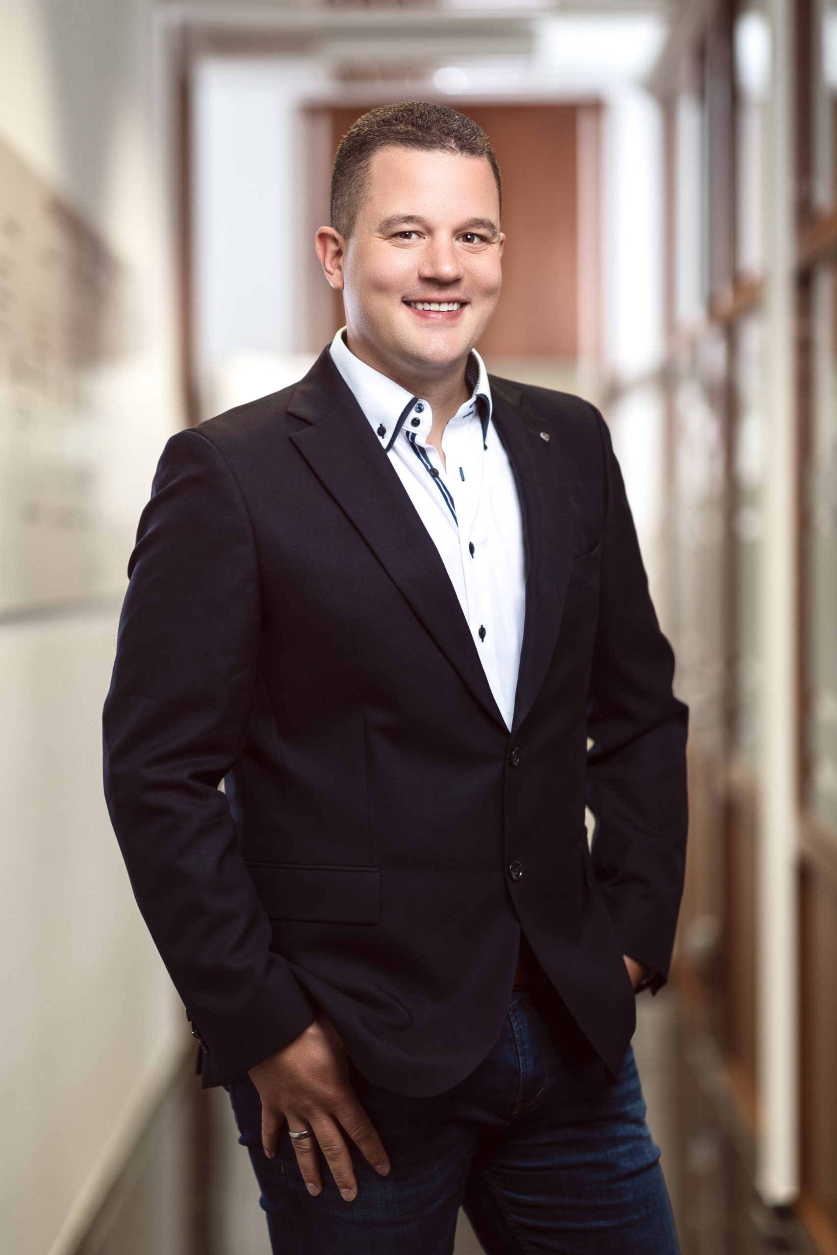 Portraitaufnahme des Inhabers in Sacko, Hemd und Jeans im Büroflur