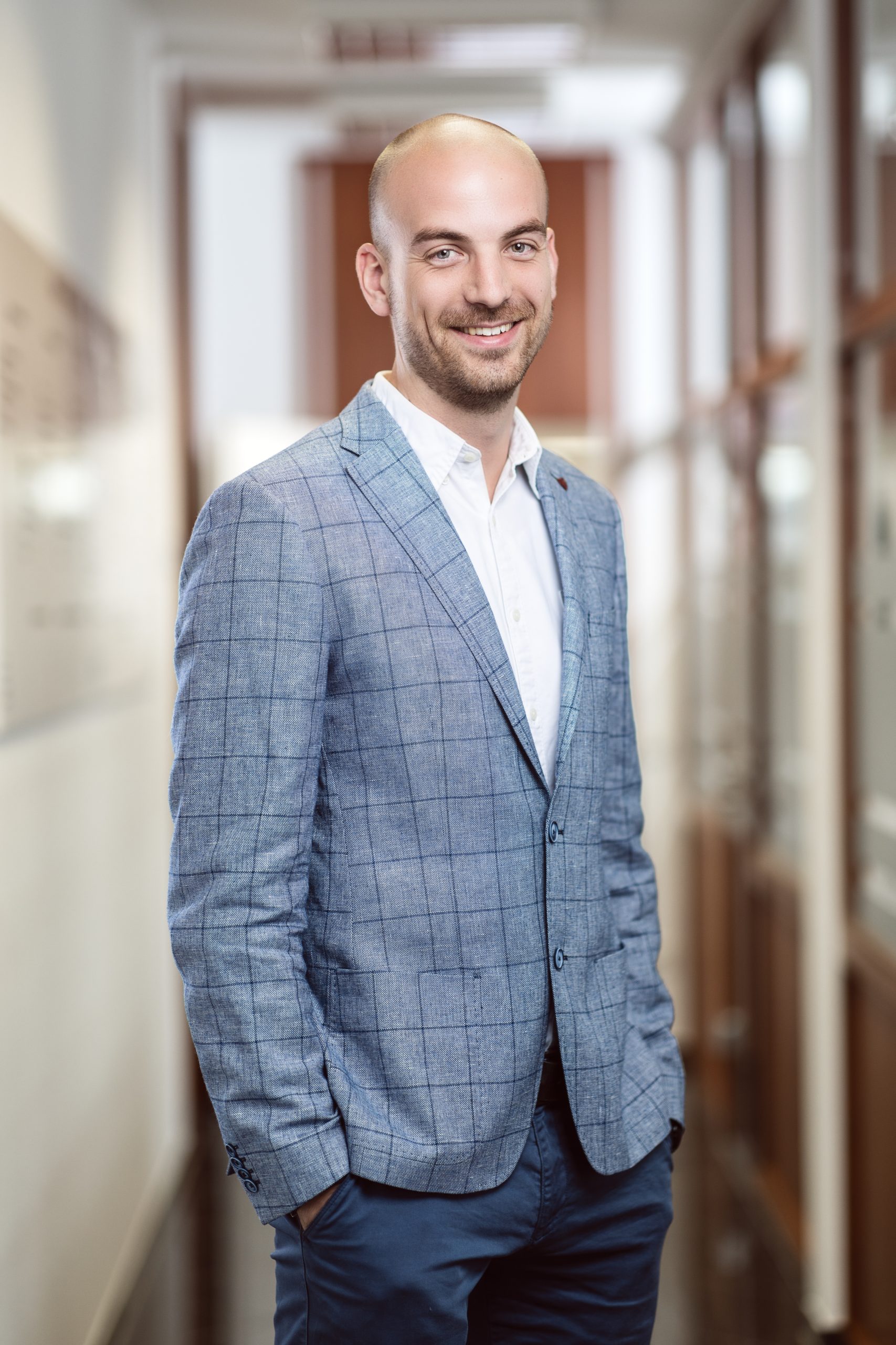 Portraitaufnahme eines Mitarbeiters IN Hemd und Sacko im Büroflur